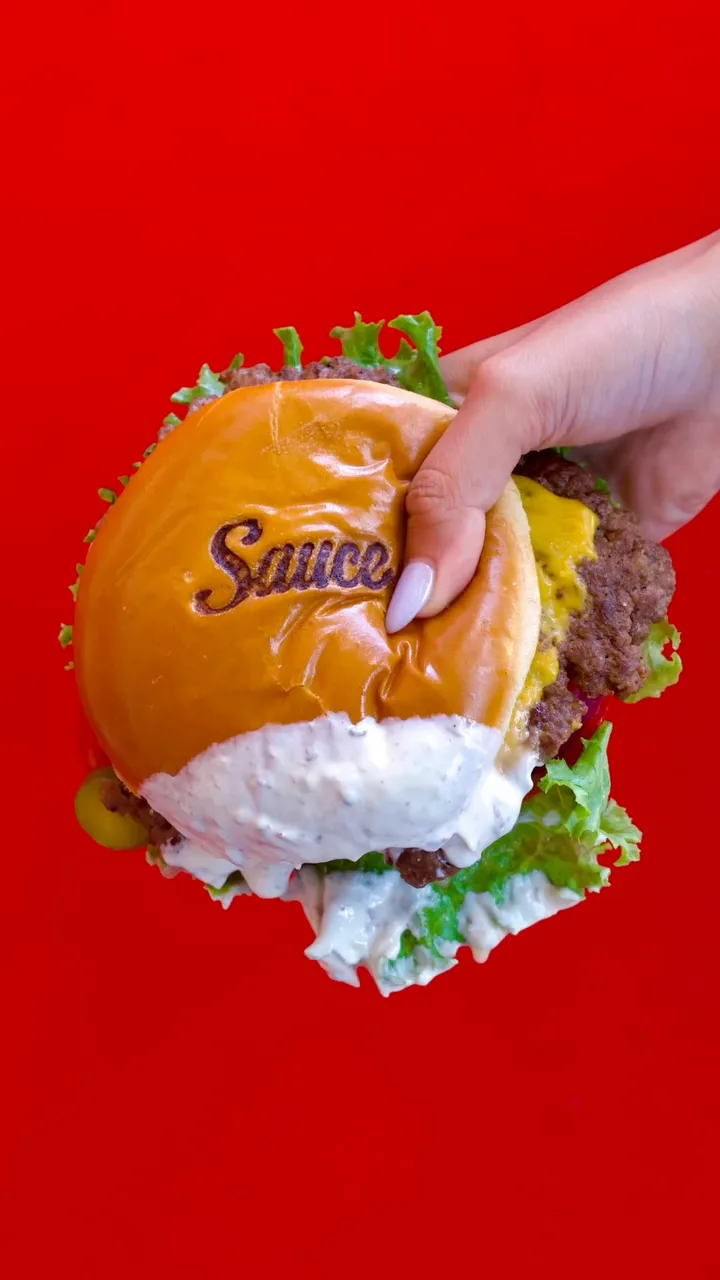 Hand holding a Sauce burger